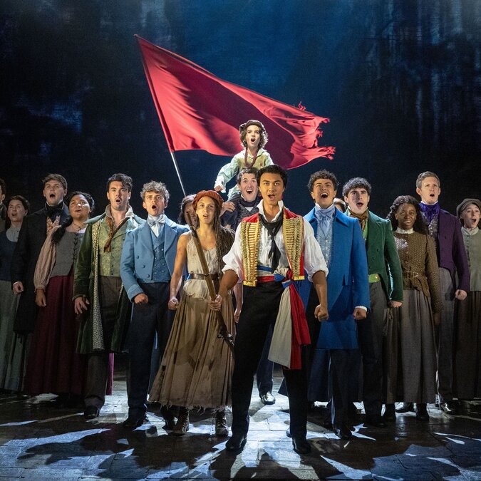 Stage ensemble standing together with a large red flag raised behind them | © Danny Kaan