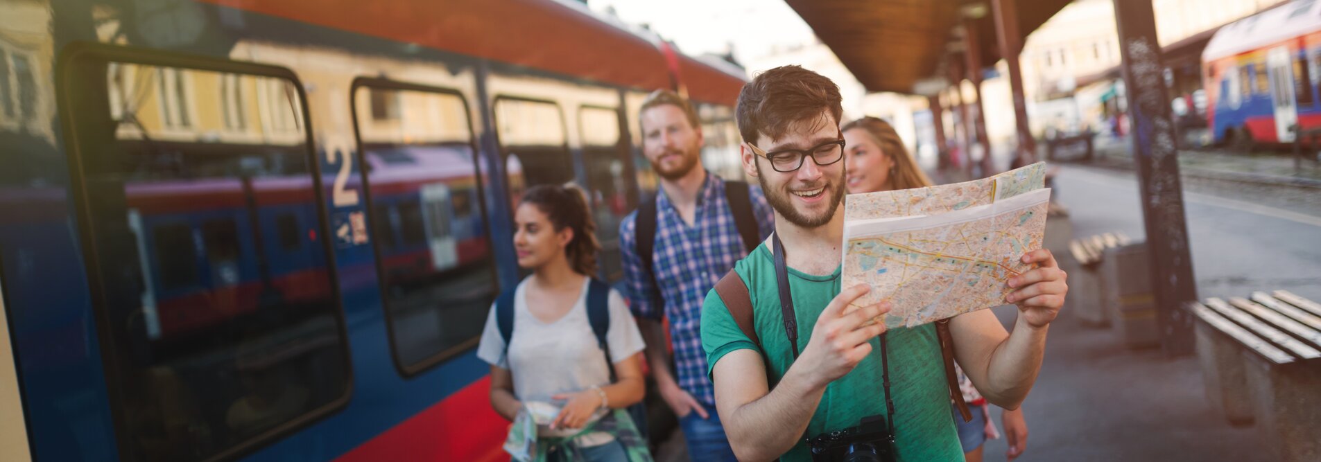 Personen mit einer Karte vor einem Zug | © Shutterstock / 501760414
