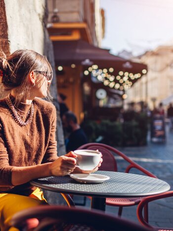 Traveller enjoying a coffee in a lively old town street | © Mariia Boiko