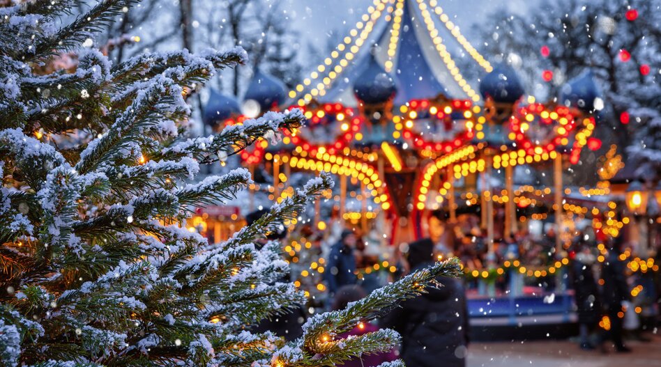 Reise in der Adventszeit nach Kopenhagen | © shutterstock / 2234281435 Beleuchtetes Karussell im Tivoli mit Christbaum voller Schnee im Vordergrund | © shutterstock / 2234281435
