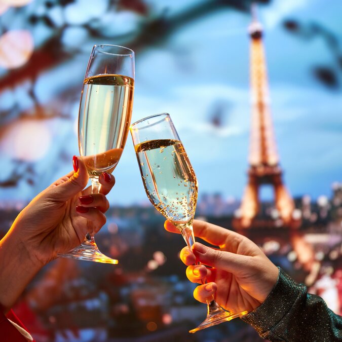 Zwei Personen stossen mit Sekt vor dem Eiffelturm an | © shutterstock / 2414756071