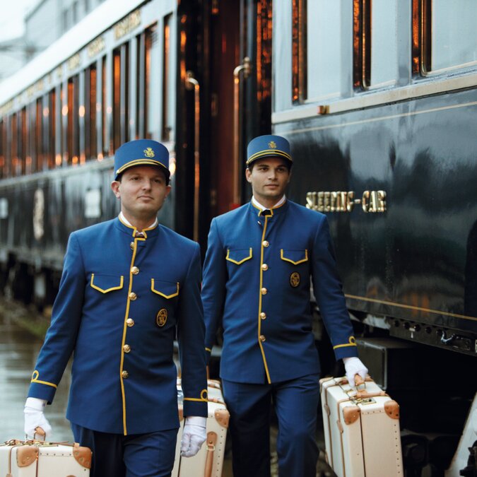 Venice Simplon-Orient-Express am Bahnsteig, zwei Stewards in blauen Uniformen tragen das Gepäck | © Belmond