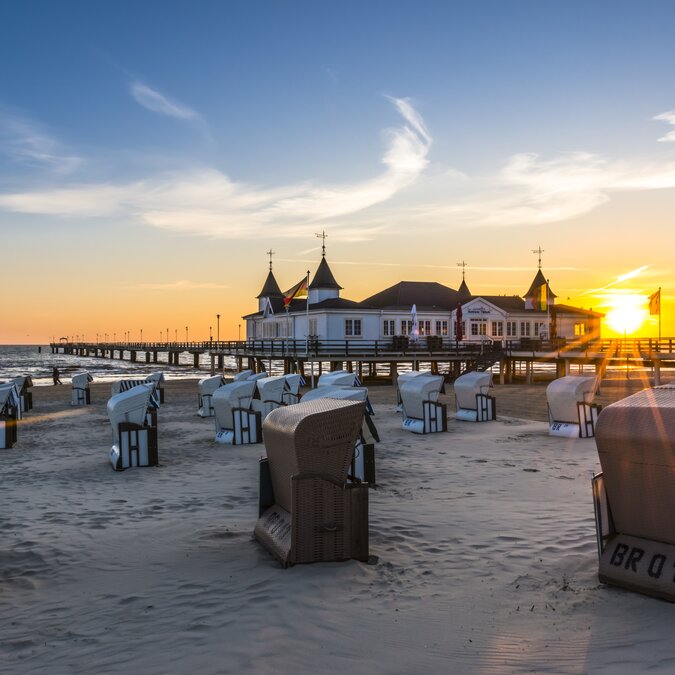 A jetty leading into the sea, on it a large white house with many turrets, in the foreground a sandy beach with many beach chairs. | © Usedom Tourismus GmbH | Dirk Bleyer 