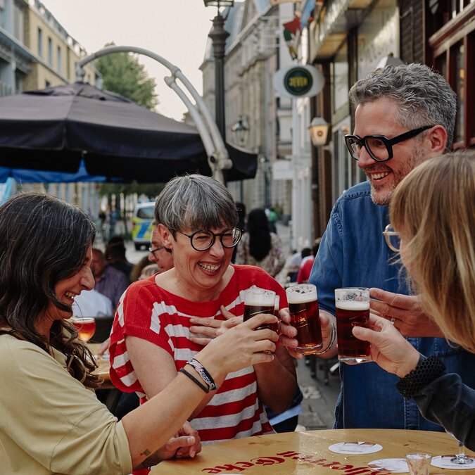 Menschen in der Düsseldorfer Altstadt die mit einem Bier anstossen.  | © Düsseldorf Marketing GmbH, Foto: Sabrina Weniger