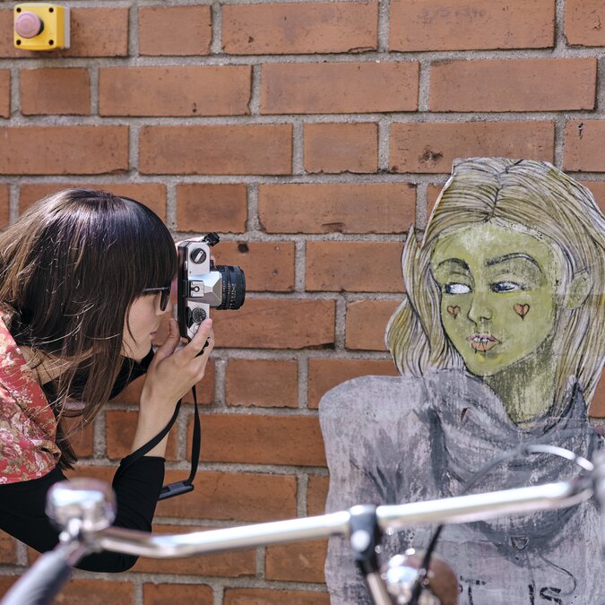 Une personne prend une photo d'un mur, au premier plan un vélo.  | © Düsseldorf Marketing GmbH, Foto: Markus Luigs