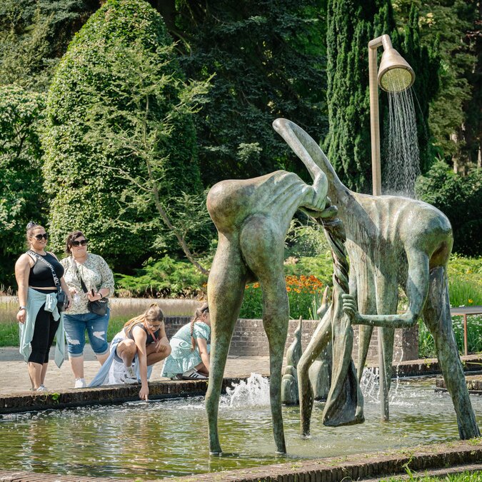 Sculpture moderne représentant une fontaine dans le parc de sculptures Middelheim, entourée de visiteurs et d'un paysage verdoyant. | © Tom Cornille – Musée Middelheim, Anvers