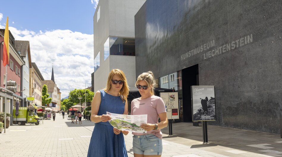 Two visitors use a map of the Liechtenstein Trail in front of the Kunstmuseum in Vaduz. | © Liechtenstein Marketing / Daniel Schwendener