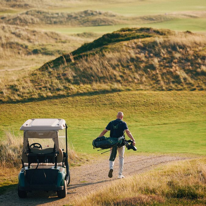 Mann auf Glofplatz mit Golfwagen | © Sylt Marketing l Peter Bender