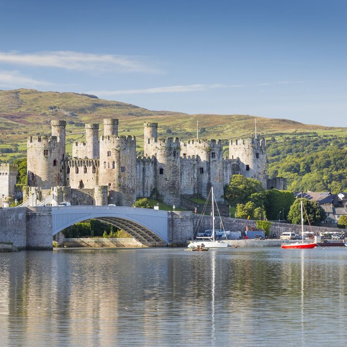 Vue sur le château médiéval de Conwy, dans le nord du Pays de Galles, avec son pont en pierre, son port paisible, ses voiliers et, en arrière-plan, les paysages verdoyants de Snowdonia. | © Crown Copyright (2026) Welsh Government