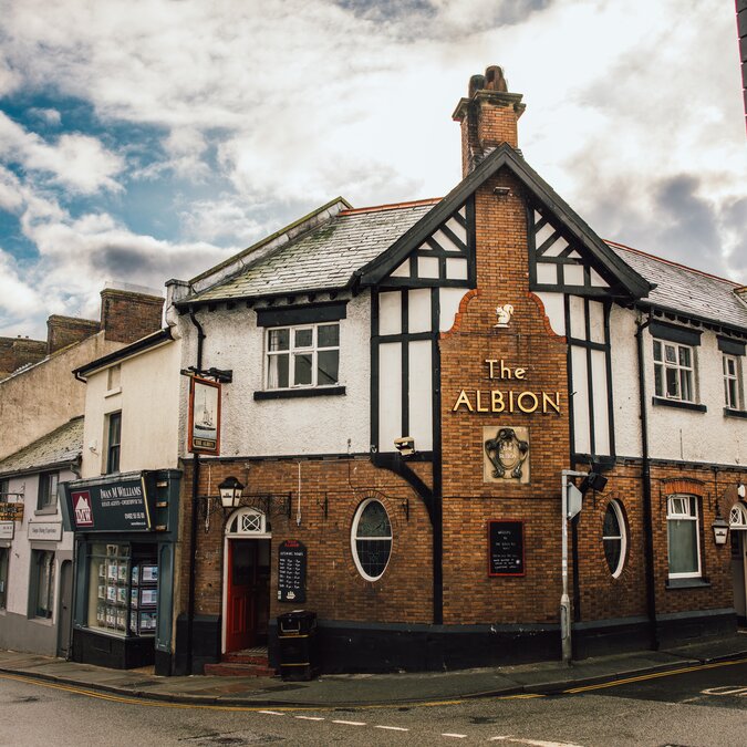 Pub traditionnel à Llandudno, au pays de Galles, avec une façade Tudor caractéristique, une architecture en briques et un décor de rue plein de charme dans une ville côtière historique. | © Crown Copyright (2026) Welsh Government