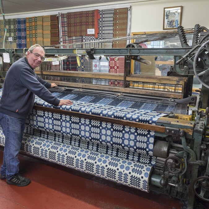 Métier à tisser historique dans une manufacture traditionnelle avec un tissu aux motifs élaborés et une technique classique de fabrication textile. | © Crown Copyright (2026) Welsh Government