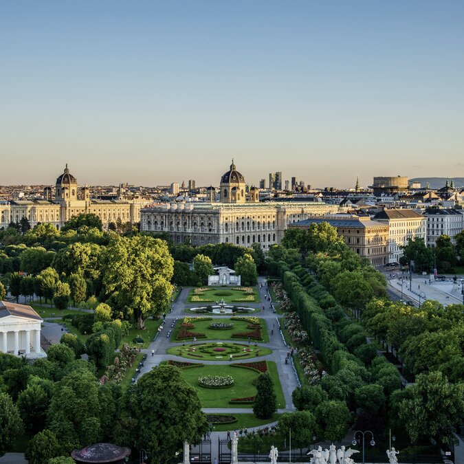 Panoramaaufnahme des Wiener Stadtzentrums mit dem Volksgarten und den historischen Museumsgebäuden im Abendlicht. | © Wien Tourismus | Christian Stemper