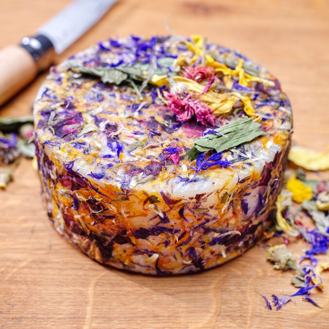 Traditional Alpine cheese with Alpine herbs and flowers, sold as a wheel in Austria. | © shutterstock / 2337113239