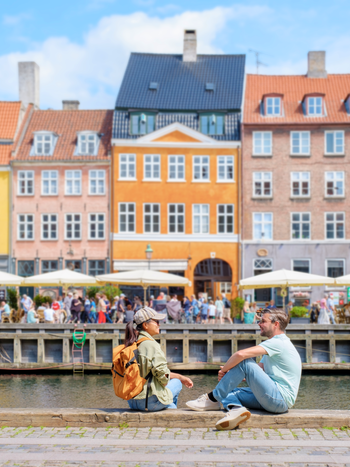 People by the canal in Copenhagen with colorful houses | © shutterstock_2492354477