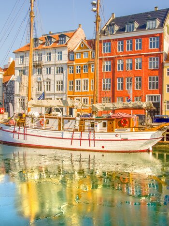 Maisons colorées et voilier blanc vintage à Nyhavn, Copenhague la vue la plus emblématique pour les voyageurs. Ville à très faible trafic, destination écologique et durable au monde. | © Shutterstock 2422860833