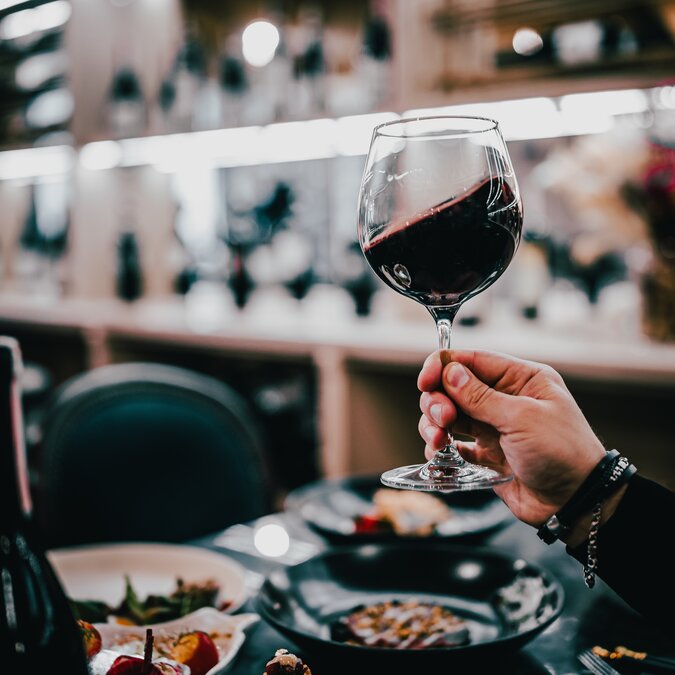 Mann, der in einem Restaurant ein Glas mit Rotwein hält | © Shutterstock 2383946131