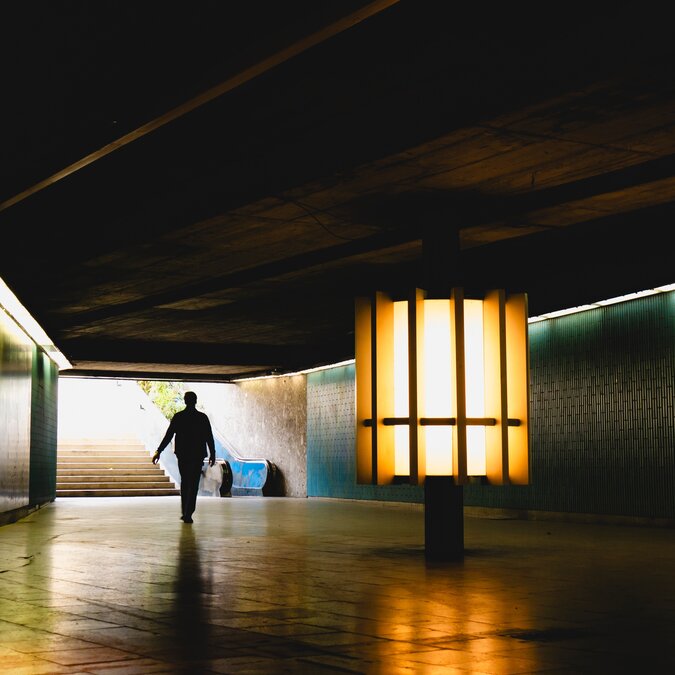 Eine Personen-Silhouette wird in eine städtische Unterführung gegossen, beleuchtet von Ambient City Lights, München, Deutschland | © Shutterstock 2481850717