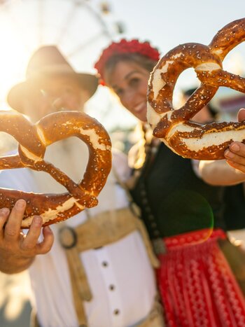 Paar mit grossen Brezeln auf dem Oktoberfest | © shutterstock / 2486289251