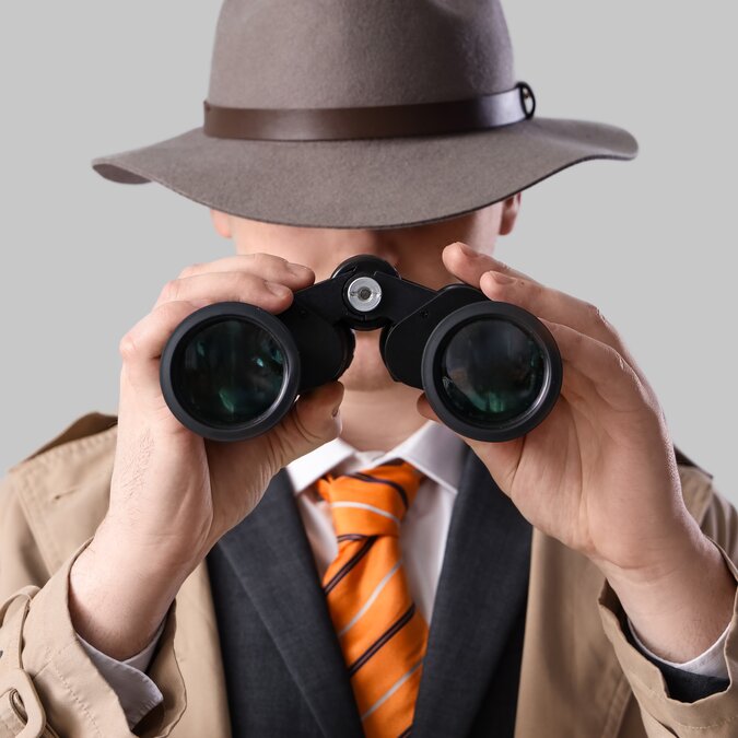 Male spy looking through binoculars on a bright background | © Shutterstock 2448197951