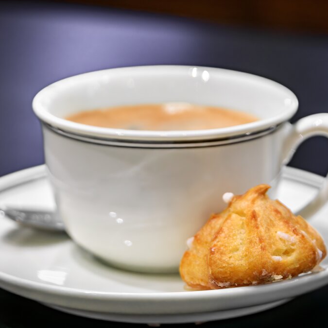 Traditioneller französischer Macaron-Keks und eine Tasse Latte, Milchkaffee, serviert zum Frühstück in einer handwerklichen Bäckerei in Straßburg, Elsass, Frankreich | © shutterstock 2407760793