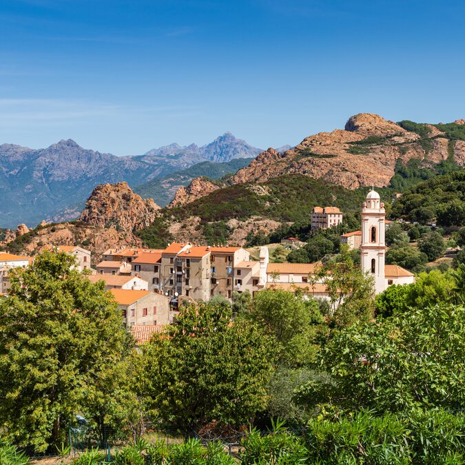Piana in Corsica, with a church, trees and mountains in the background. | © shutterstock 2225283733