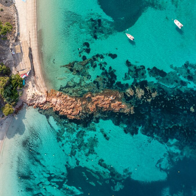 Türkisblauen Bucht am Strand Palombaggia auf Korsika mit Sandstrand, Felsen, klarem Wasser und kleinen Booten in unberührter Natur. | © shutterstock 2418172677