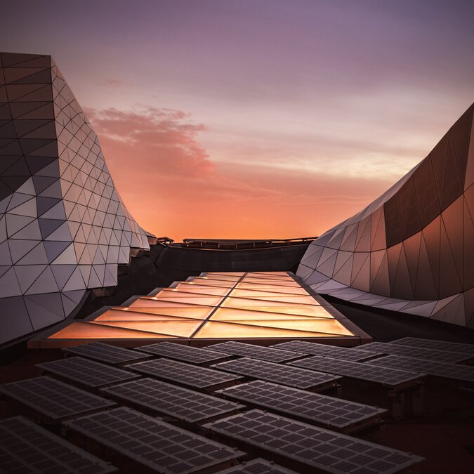 Détail du musée Confluence à Lyon, avec son style architectural unique et ses matériaux modernes en acier et en verre. Maquettes photovoltaïques et lumière orange sur l'écologie, l'alerte, l'électricité, l'évolution.