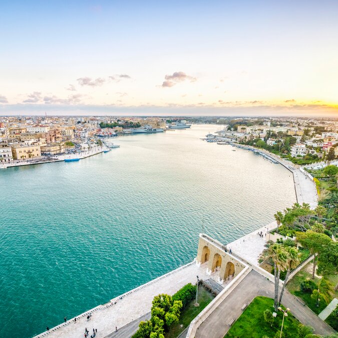 Vue sur le canal du port de Brindisi au coucher du soleil avec promenade en bord de mer et eaux turquoise. | © shutterstock_790146814