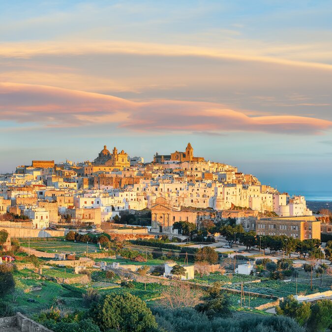 Vieille ville historique aux maisons claires perchée sur une colline baignée par la lumière du coucher du soleil. | © shutterstock_2270878975