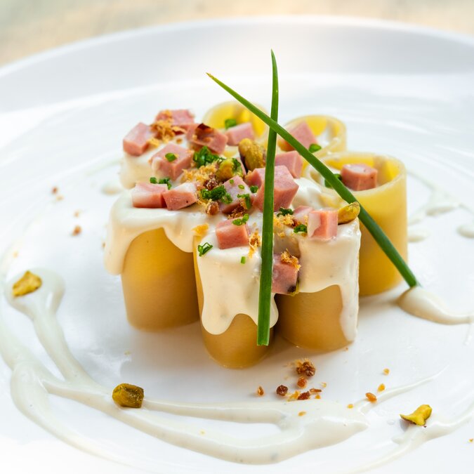 Paccheri Italienische frische traditionelle Pasta mit Mortadella Bologna Schinken, Käse, Sahne, Pistazien, schöne Garnierung Kunst plating professionellen Küchenchef feines Essen in natürlichem Gegenlicht, Essen im Freien | © Shutterstock 1445388362