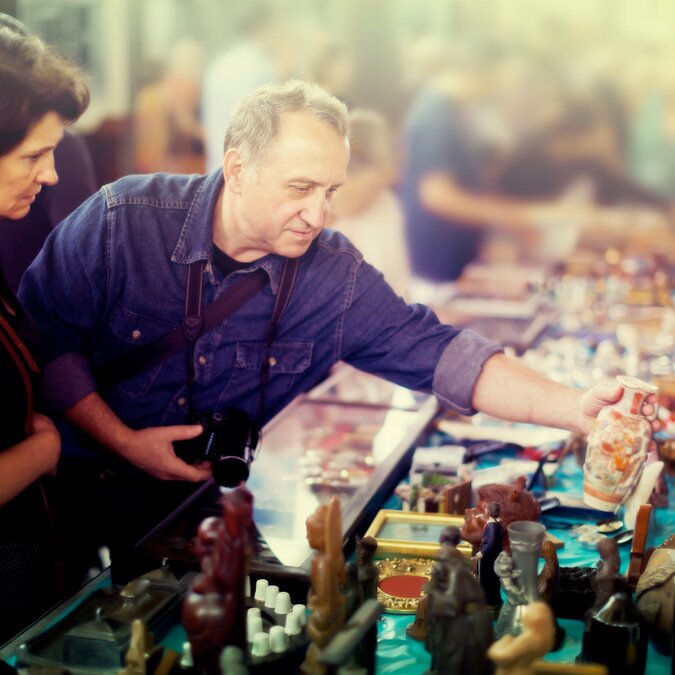 Cheerful couple of tourists study the range of flea market