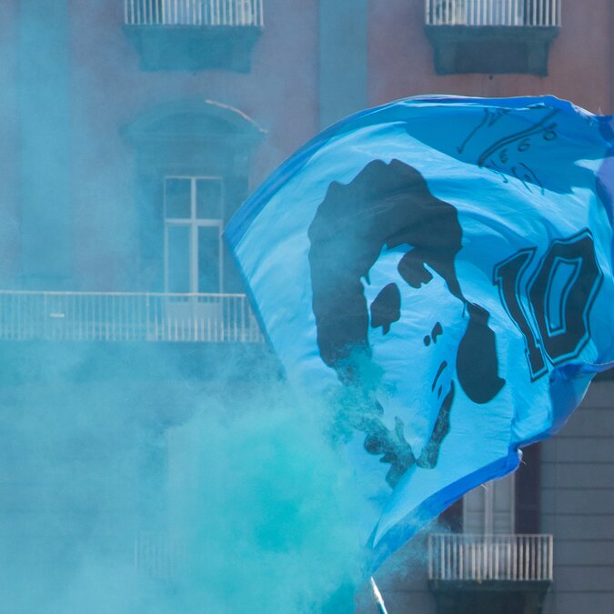Flag with Maradonna and blue haze on a street before a football match | © shutterstock / 2309064385