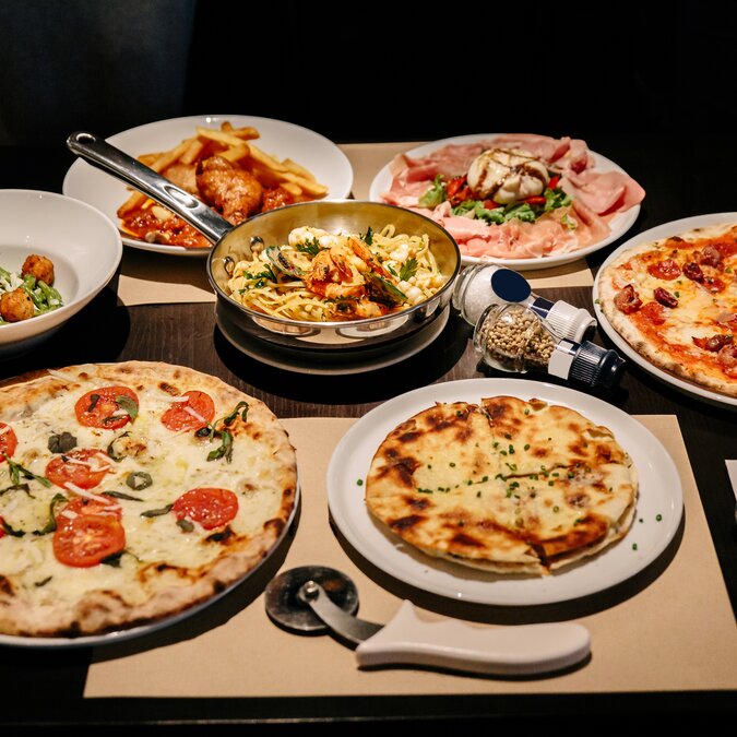 Hot served Italian dishes: Pizza Carbonara and Carpres with Pizza Cutter, Cold Cuts with Burrata Cheese, Puccia with Black Truffle and Linguini Seafood. | © Shutterstock 1389645959