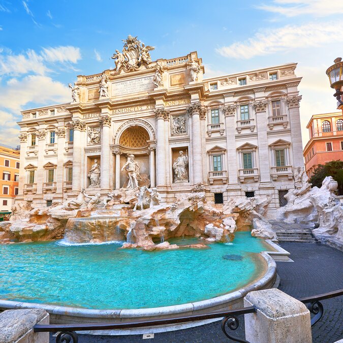 Fontaine de Trevi à Rome, Italie. Vieille fontaine. Statues romaines sur la place de l'ancienne ville médiévale, entre les maisons italiennes traditionnelles et les réverbères. Célèbre symbole de la ville. Destination de vacances. | © Shutterstock 1373532875