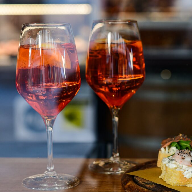 Apéritif italien aperol spritz avec tranche d'orange dans de grands verres ronds sur une table en bois dans un bar en Italie. vue à travers la fenêtre du bar à Florence Rome Milan Venise Italie. focus sélectif | © Shutterstock 1642351627