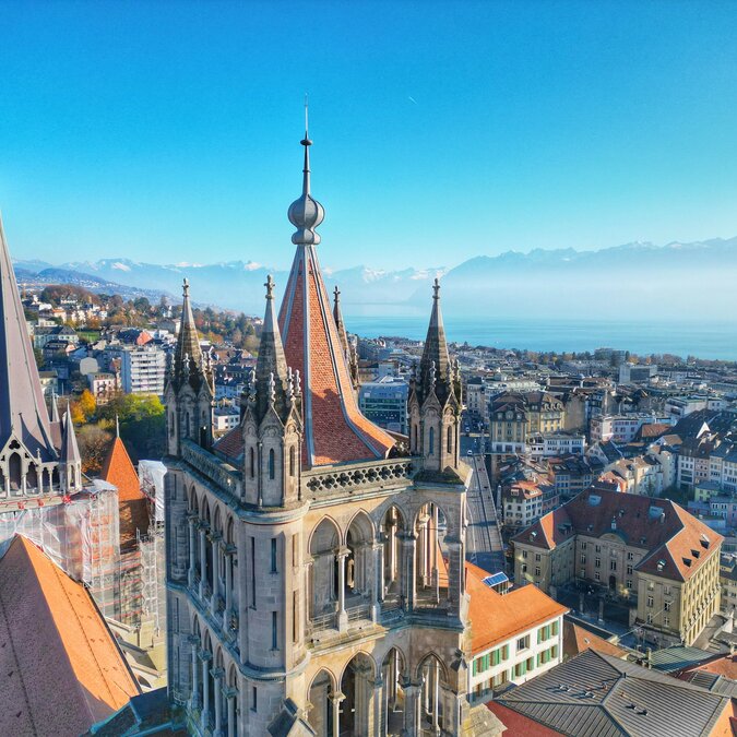 Blick über die Spitze der Kathedrale auf die darunterliegende Stadt und den Genfersee | © shutterstock / 2415664901