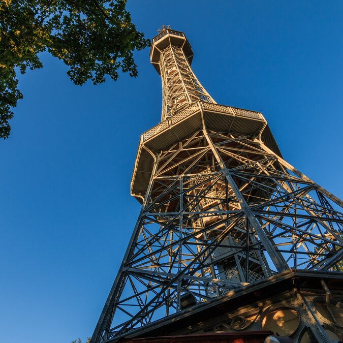 Old Petrin radio tower made of steel in Prague on the Petrin hill with view from the pedestal in the district Lesser Town with observation deck in the sunshine and blue sky